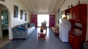 A spacious living area with a blue sofa, a wooden coffee table, and a red cabinet. - Rainbow Beach - Apartment with an amazing seaview (Calibishie)