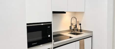 A compact kitchen with a built-in microwave, a sink, and a dishwasher.