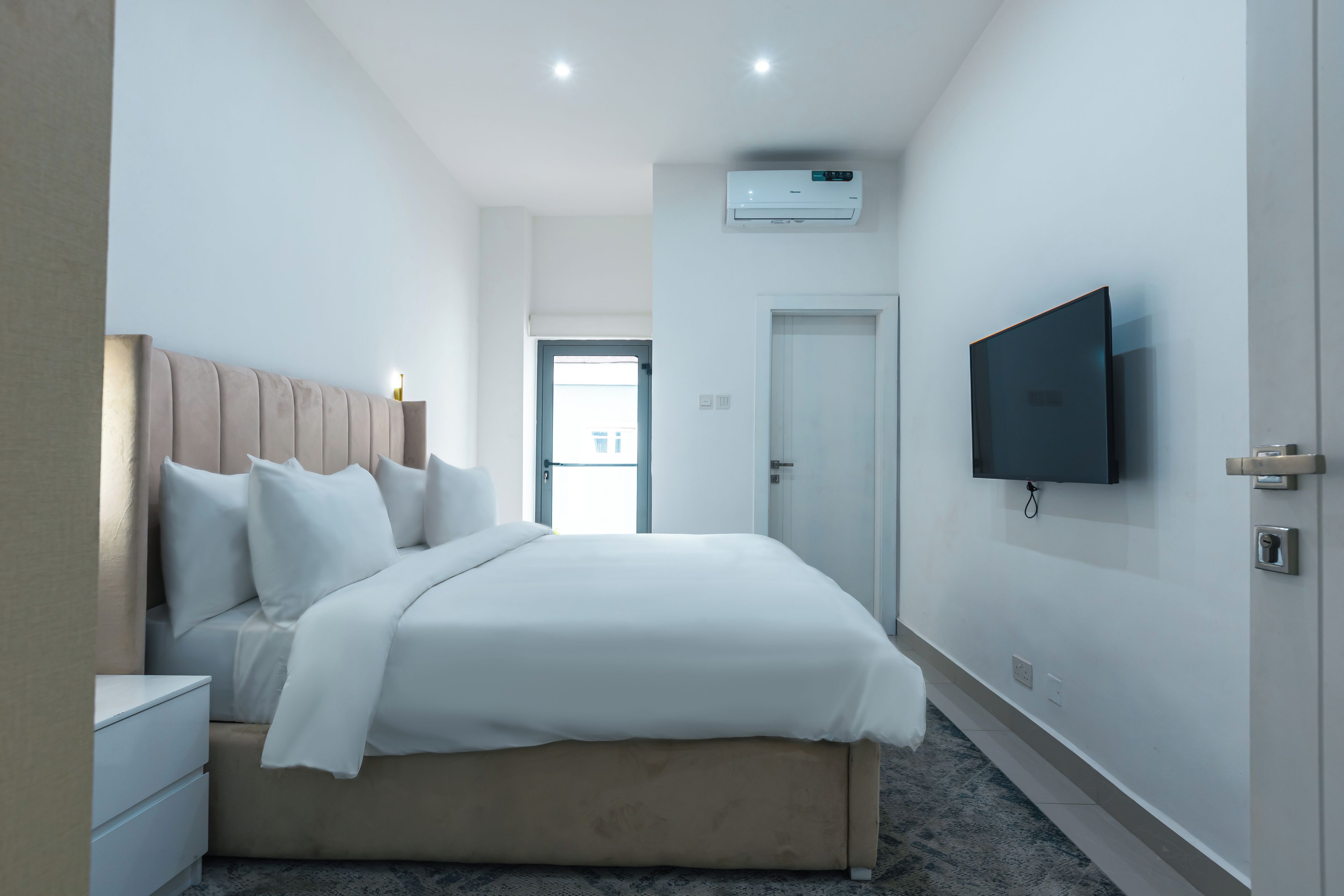 Una habitación de hotel con cama, mesitas de noche, televisor y aire acondicionado.