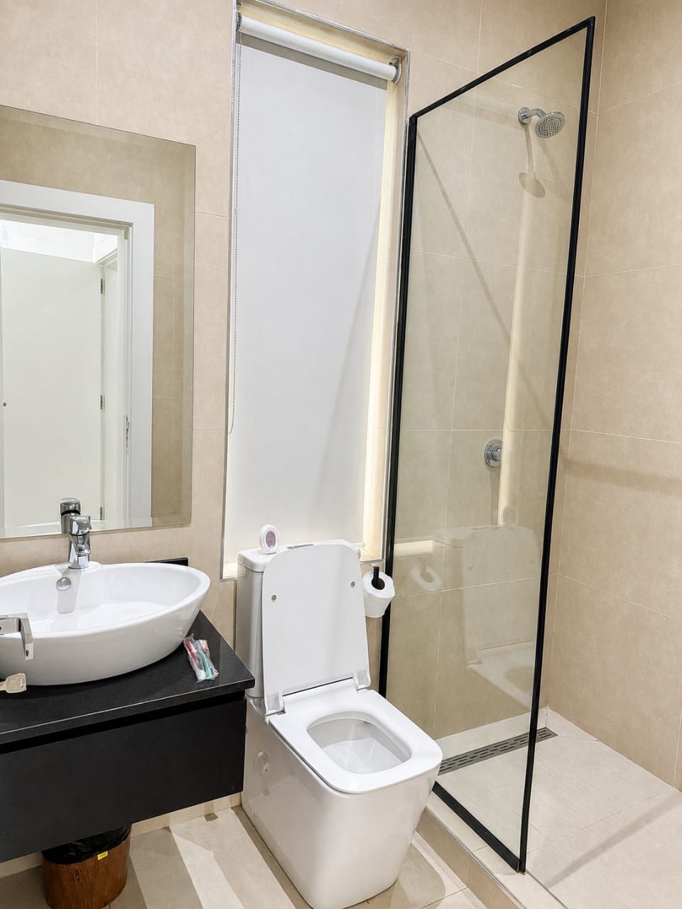 A modern bathroom with a glass-enclosed shower, a white toilet, and a sink with a black countertop.