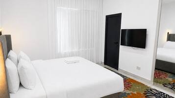 Une chambre d’hôtel avec un lit, une télévision, une porte et un miroir.