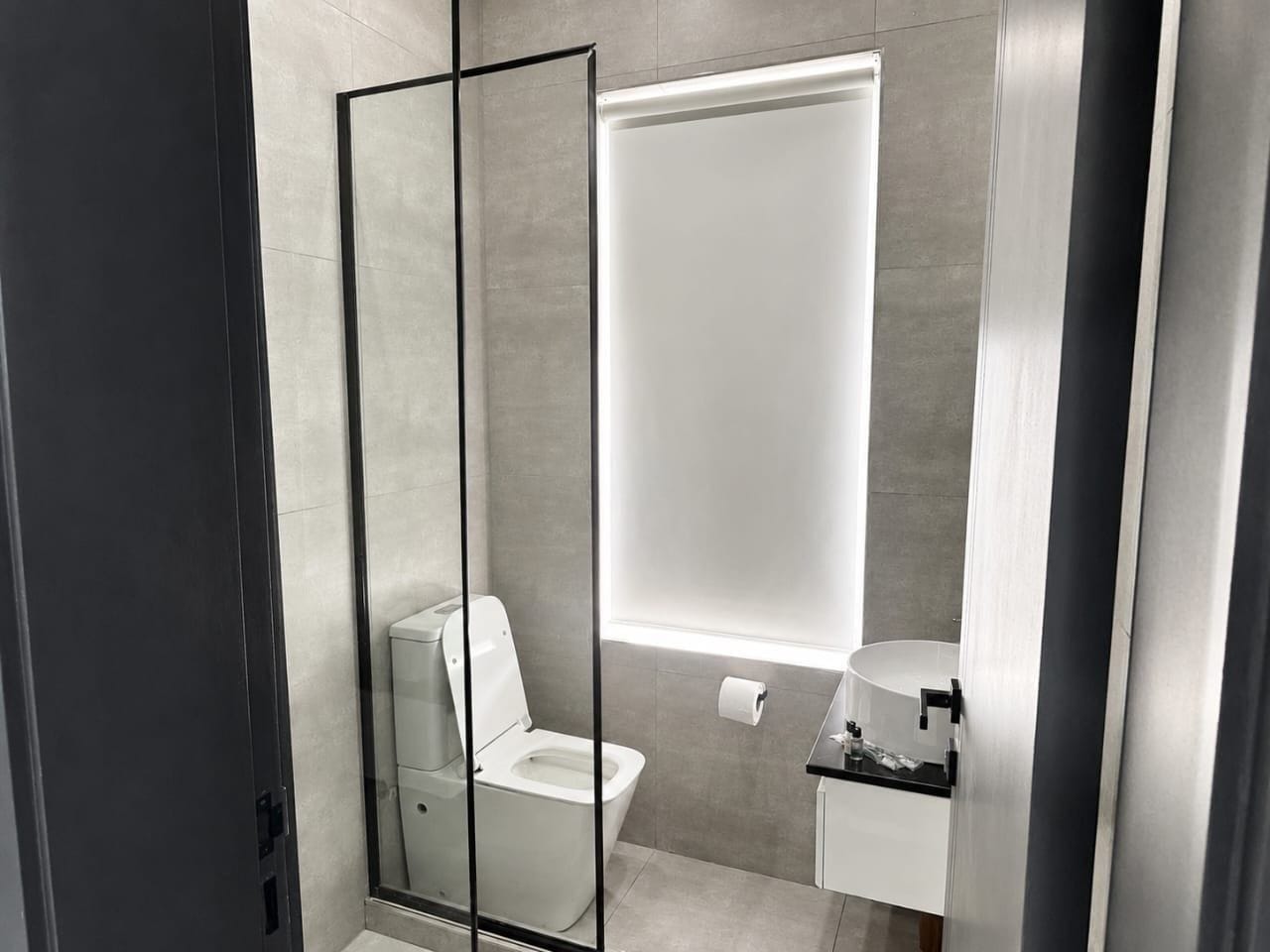 A modern bathroom with a toilet, a sink, and a mirror.