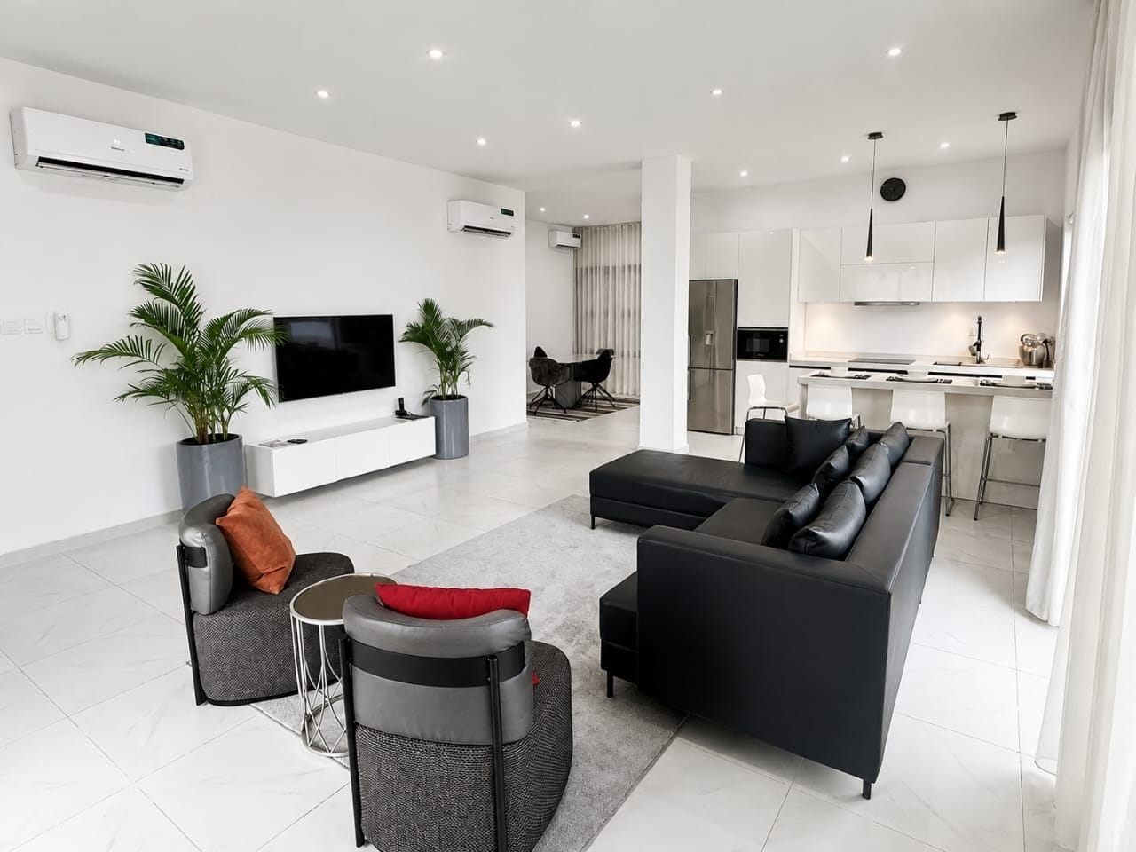 Un salon moderne avec un canapé, une table basse et un téléviseur. Il y a également un coin cuisine avec une table à manger et des chaises.