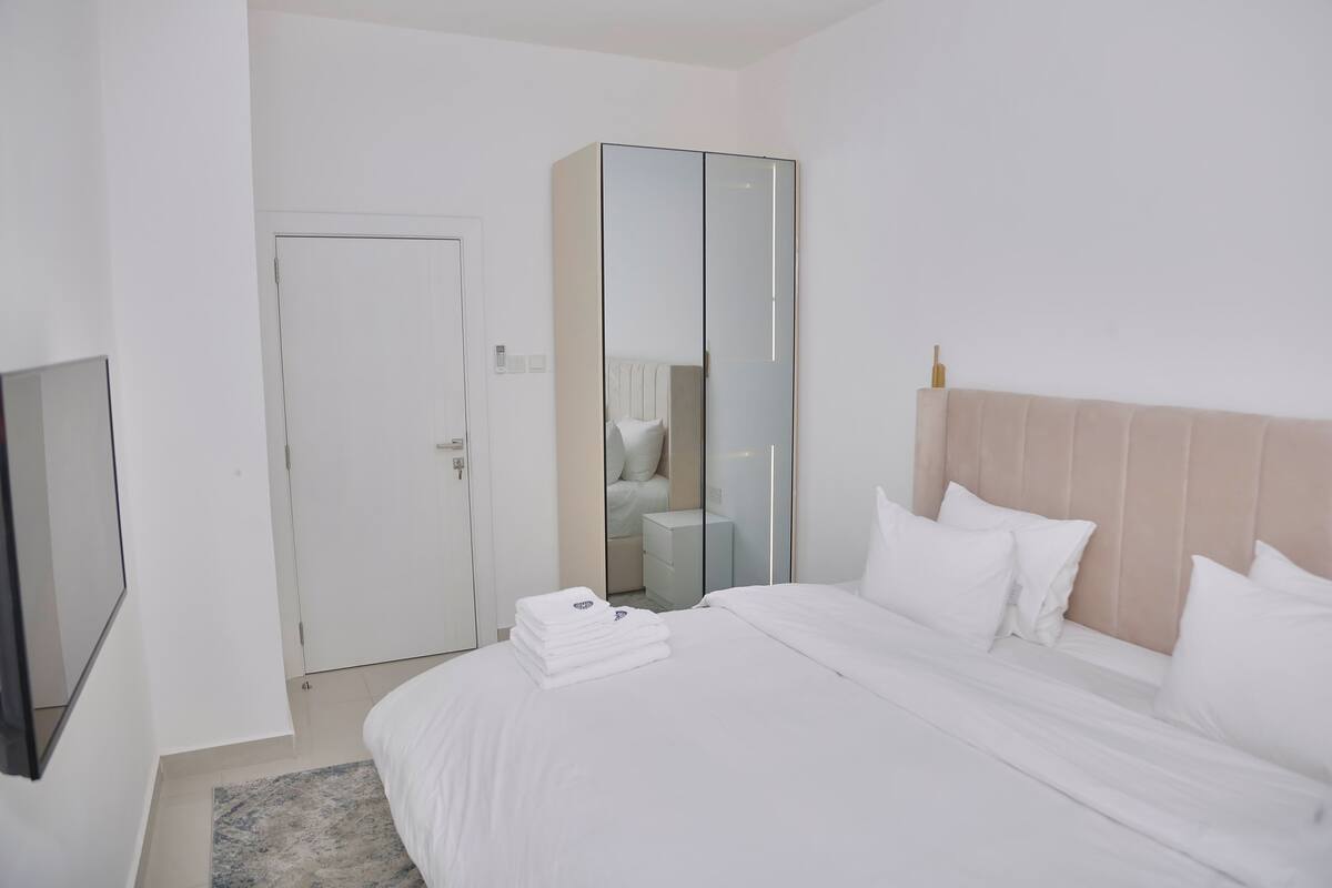 Une chambre d’hôtel avec un lit, une armoire, un miroir et un téléviseur.