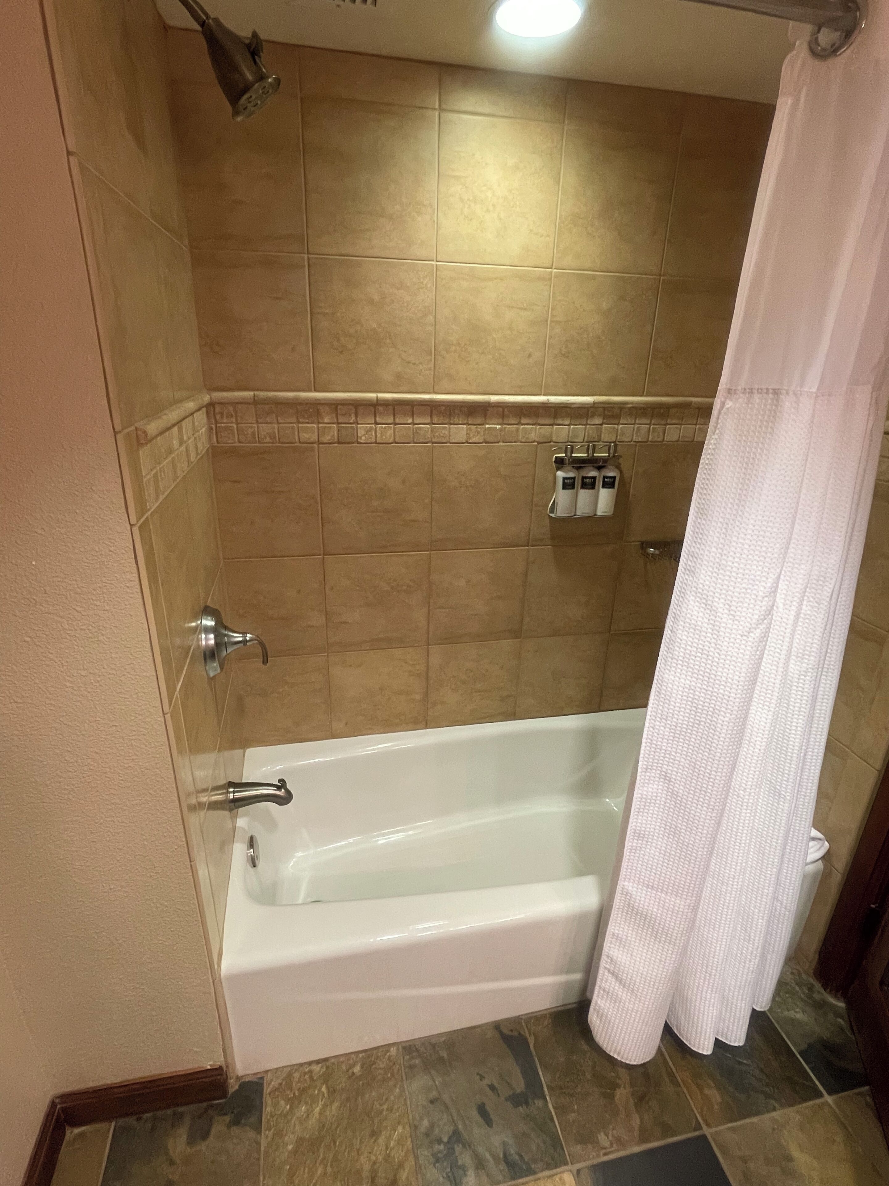 Un bagno con vasca, doccia e pareti in piastrelle.