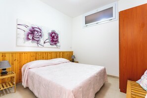 A bedroom with a wooden headboard, a bed with a pink bedspread, a bedside table with a lamp, and two floral paintings on the wall. - 3977 Appartamento di Stefy by Barbarhouse (Porto Cesareo)