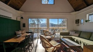 Une pièce spacieuse avec un plafond haut, de grandes fenêtres, un coin repas et un espace salon confortable.