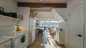 Une cuisine avec des meubles blancs, une cuisinière et un coin repas comprenant une table et des chaises.