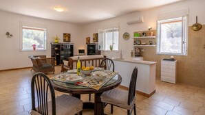 A modern kitchen with a dining area, featuring a round table, chairs, and a central island. - Casamarmora Al Carrubo (Sicilia)