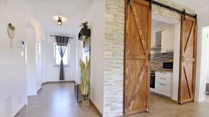 A modern interior with a hallway leading to a kitchen area, featuring sliding barn doors and a stone accent wall.