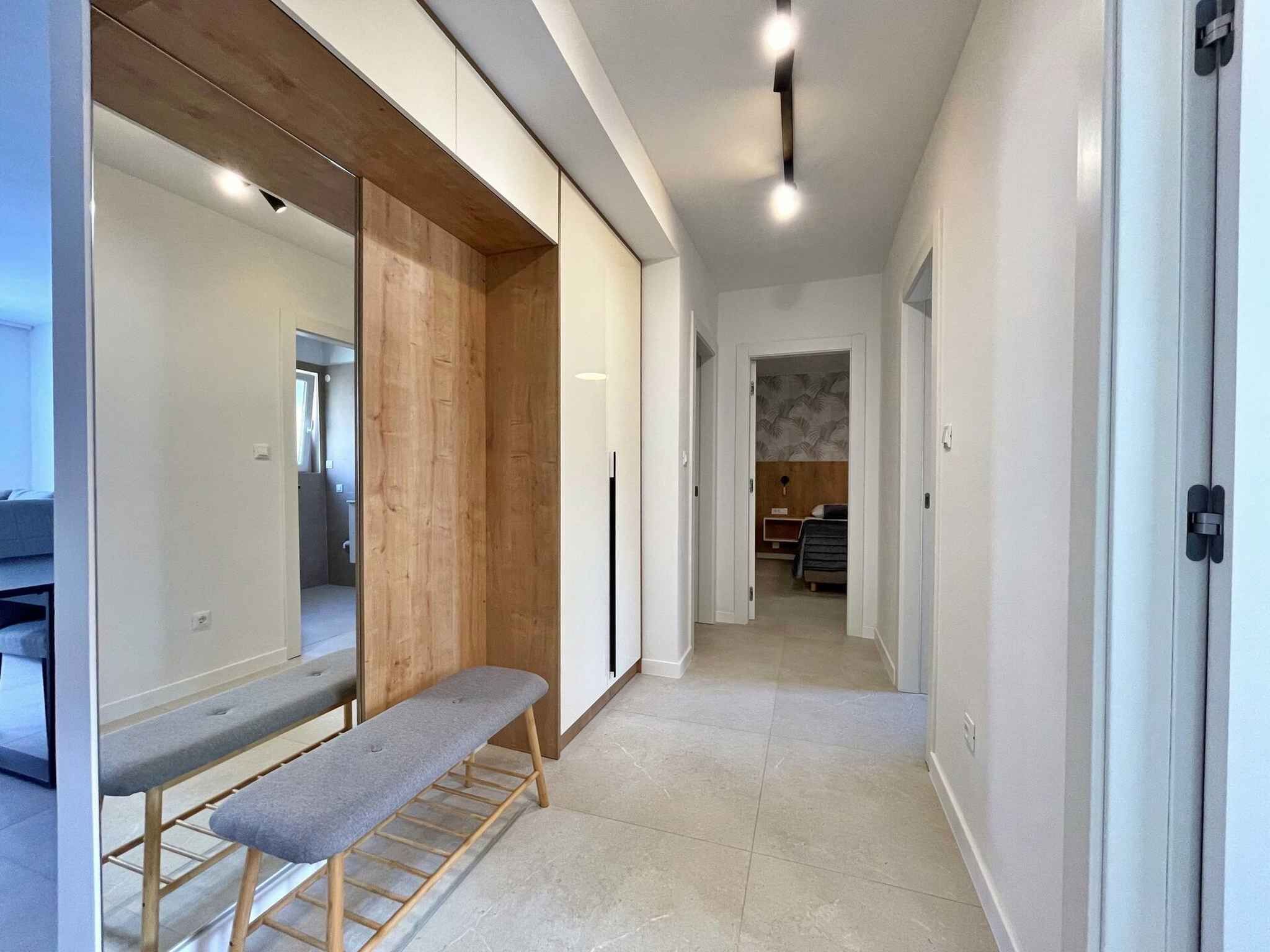 Un couloir moderne avec un banc, un lambris en bois et un lit en arrière-plan.