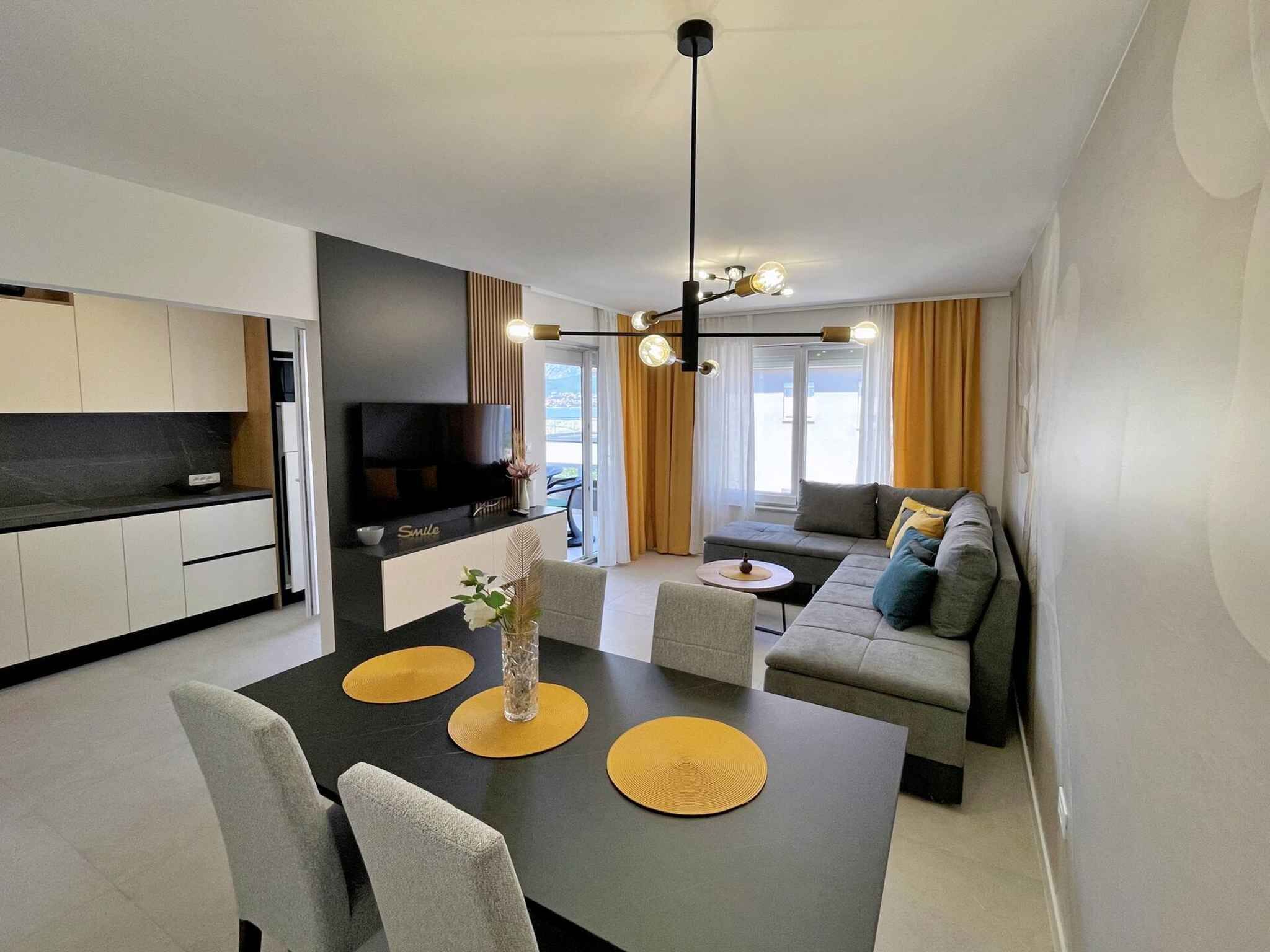 Una sala de estar moderna con un sofá, una mesa de comedor con individuales y un televisor montado en la pared.