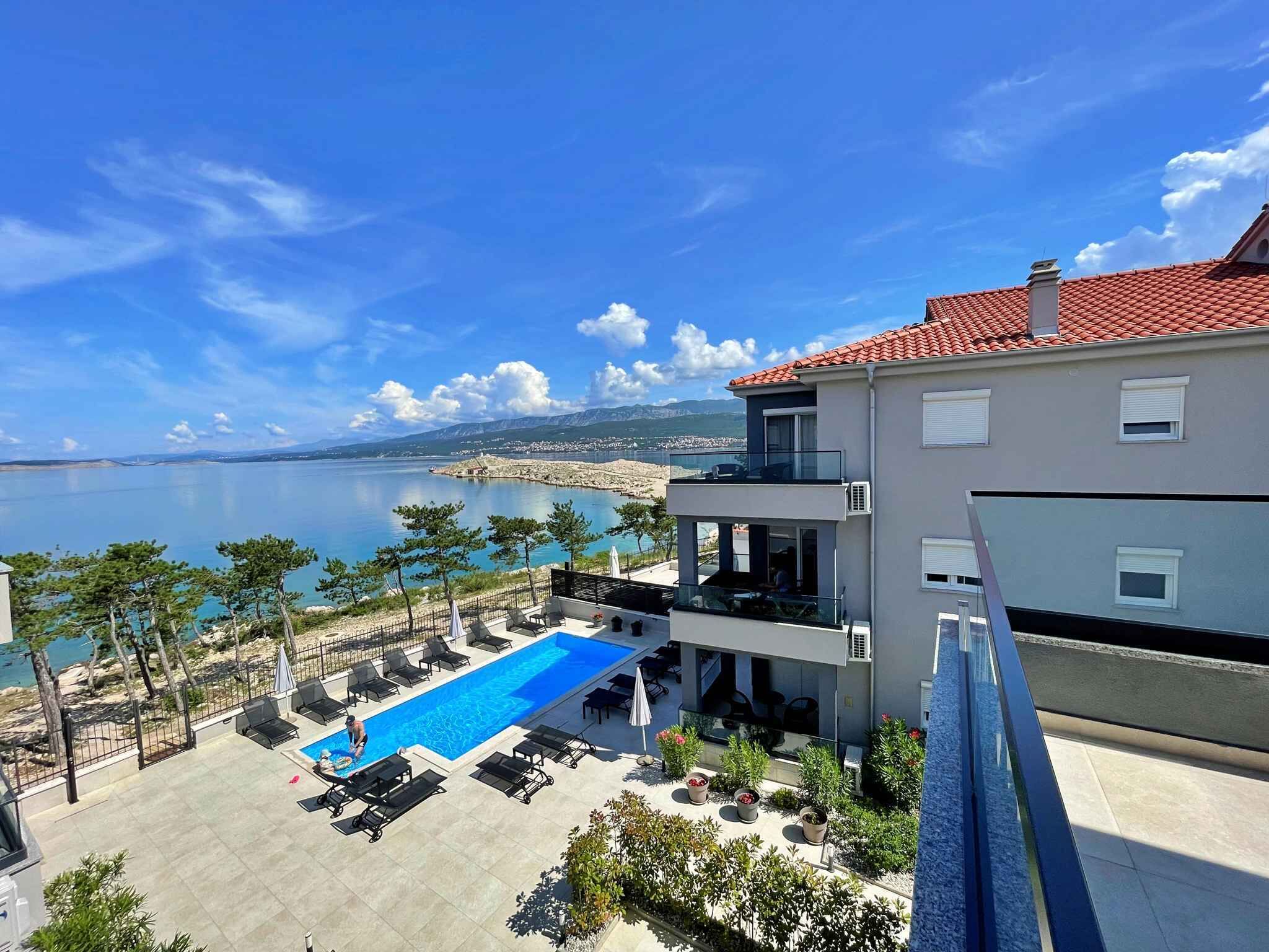 A modern building with a rooftop pool overlooking a scenic coastal view.