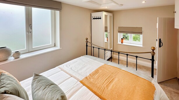 Ein Schlafzimmer mit Bett, Kissen, einem Kleiderschrank und einem Fenster.