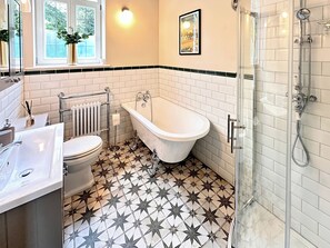 Een badkamer met een witte badkuip, toilet en douchecabine met glazen deur.