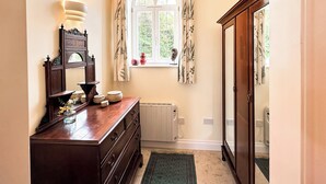 A hallway with a wooden dresser, a radiator, a window with curtains, and a mirror. - 2 bedroom accommodation in Wenhaston, near Halesworth (Wenhaston, near Halesworth)