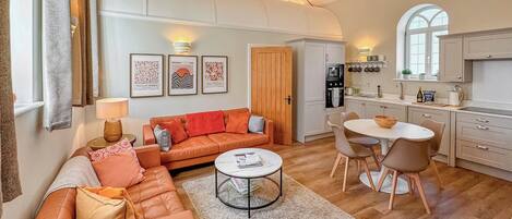A modern living room with a sofa, coffee table, and dining area.