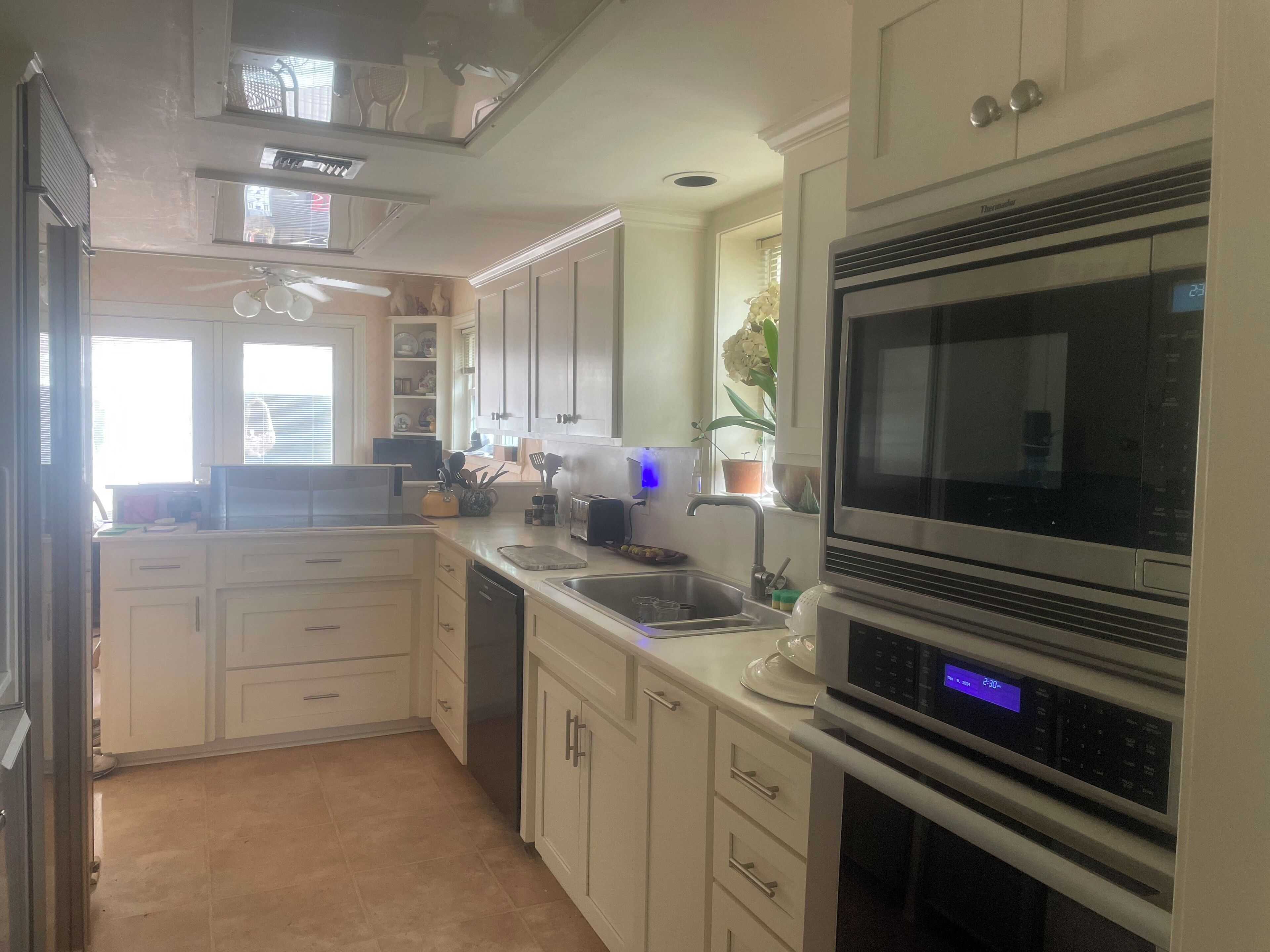 A modern kitchen with white cabinets, a stainless steel microwave, and a dishwasher.