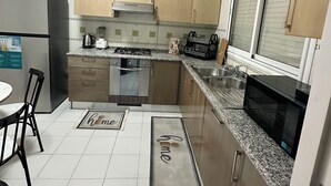 A modern kitchen with stainless steel appliances, wooden cabinets, and a granite countertop. - Stunning 3 Bedroom Apartment in Khezema, Sousse Just 5 Minutes From the Beach! (Sousse)