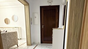 A hallway with a marble floor, a wooden door, and a white cabinet. - Stunning 3 Bedroom Apartment in Khezema, Sousse Just 5 Minutes From the Beach! (Sousse)