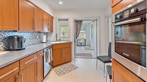 A modern kitchen with wooden cabinets, a Bosch oven, and a coffee maker.