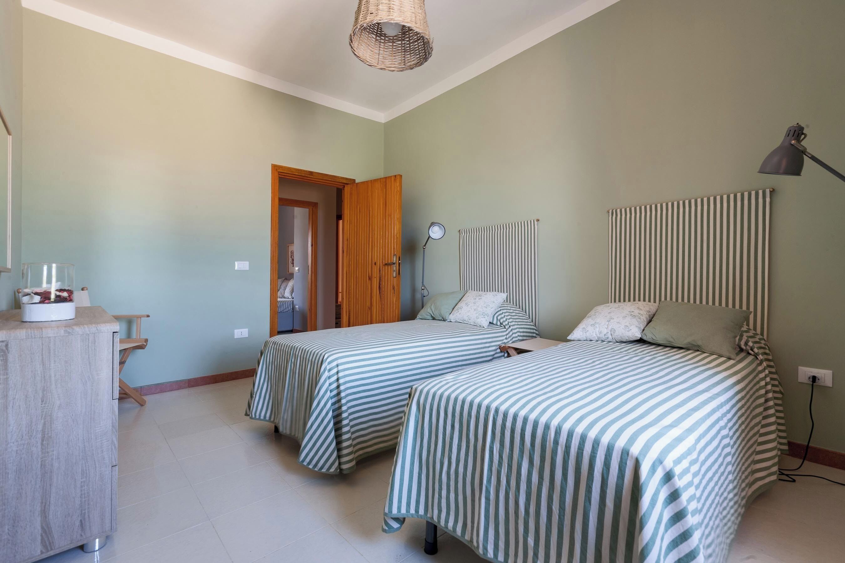 Un dormitorio con dos camas, un aparador de madera, una lámpara y un radiador.