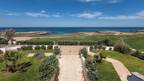 A landscaped garden with a stone pathway leading to a view of the sea.