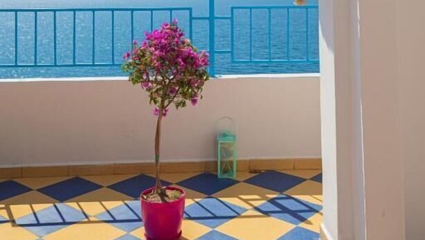 A balcony with a potted plant, a hanging light fixture, and a view of the sea. - Villa Gaudium (Orikum)