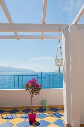 A balcony with a potted plant, a hanging light fixture, and a view of the sea.