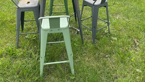 Un espacio al aire libre con césped, una mesa de madera y dos sillas de metal.