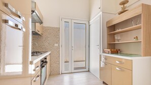 A modern kitchen with a built-in oven, a stainless steel range hood, and a double door leading to a balcony. - 3960 Villa Colle Azzurro by Barbarhouse (Porto Cesareo)