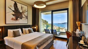 Una habitación de hotel moderna con una cama grande, un escritorio con cafetera y vistas al mar.