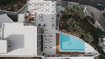 An aerial view of a hotel with a rooftop pool, outdoor seating area, and a landscaped garden.