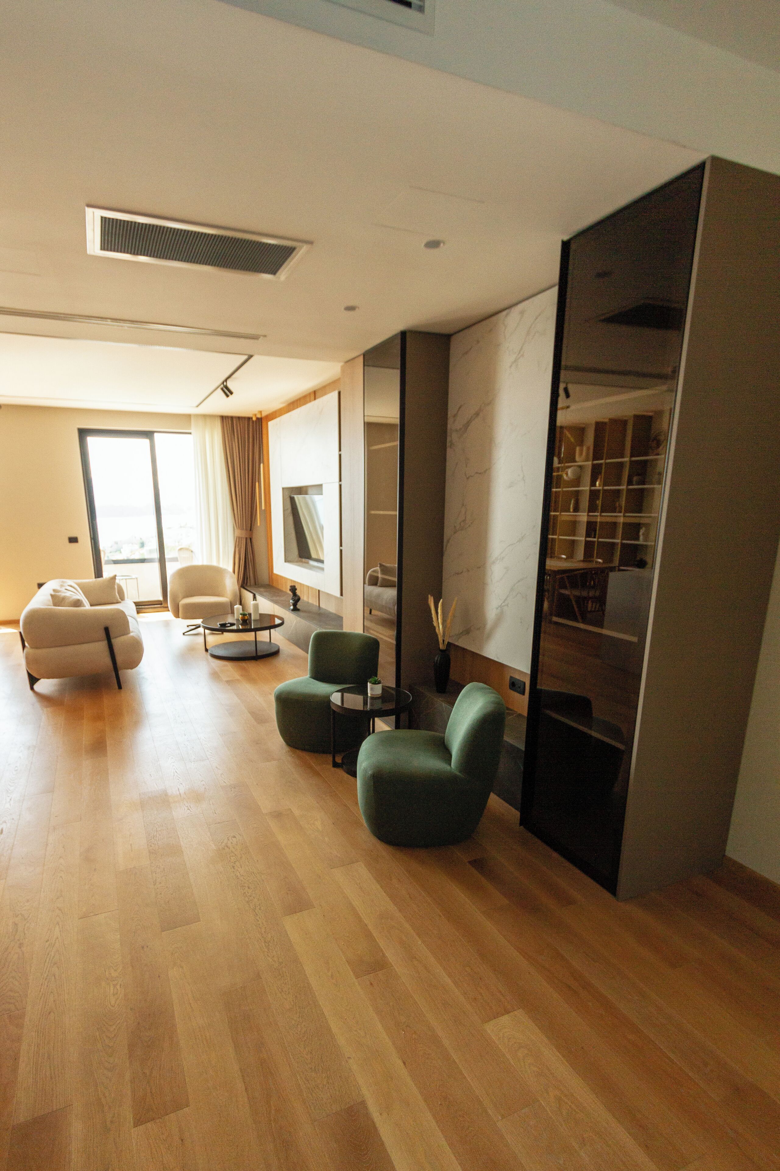 A modern living room with a sofa, armchairs, a coffee table, and a TV.