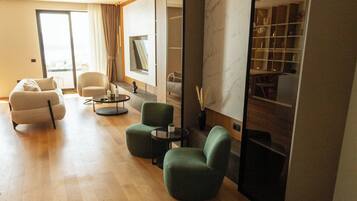 A modern living room with a sofa, armchairs, a coffee table, and a TV.