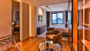 Habitación de hotel moderna con cama, zona de estar y un gran ventanal con vistas al mar.