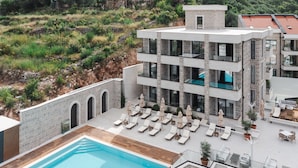 A modern hotel with a rooftop pool, multiple balconies, and outdoor seating areas. - Hotel kingStone Budva (Przno)