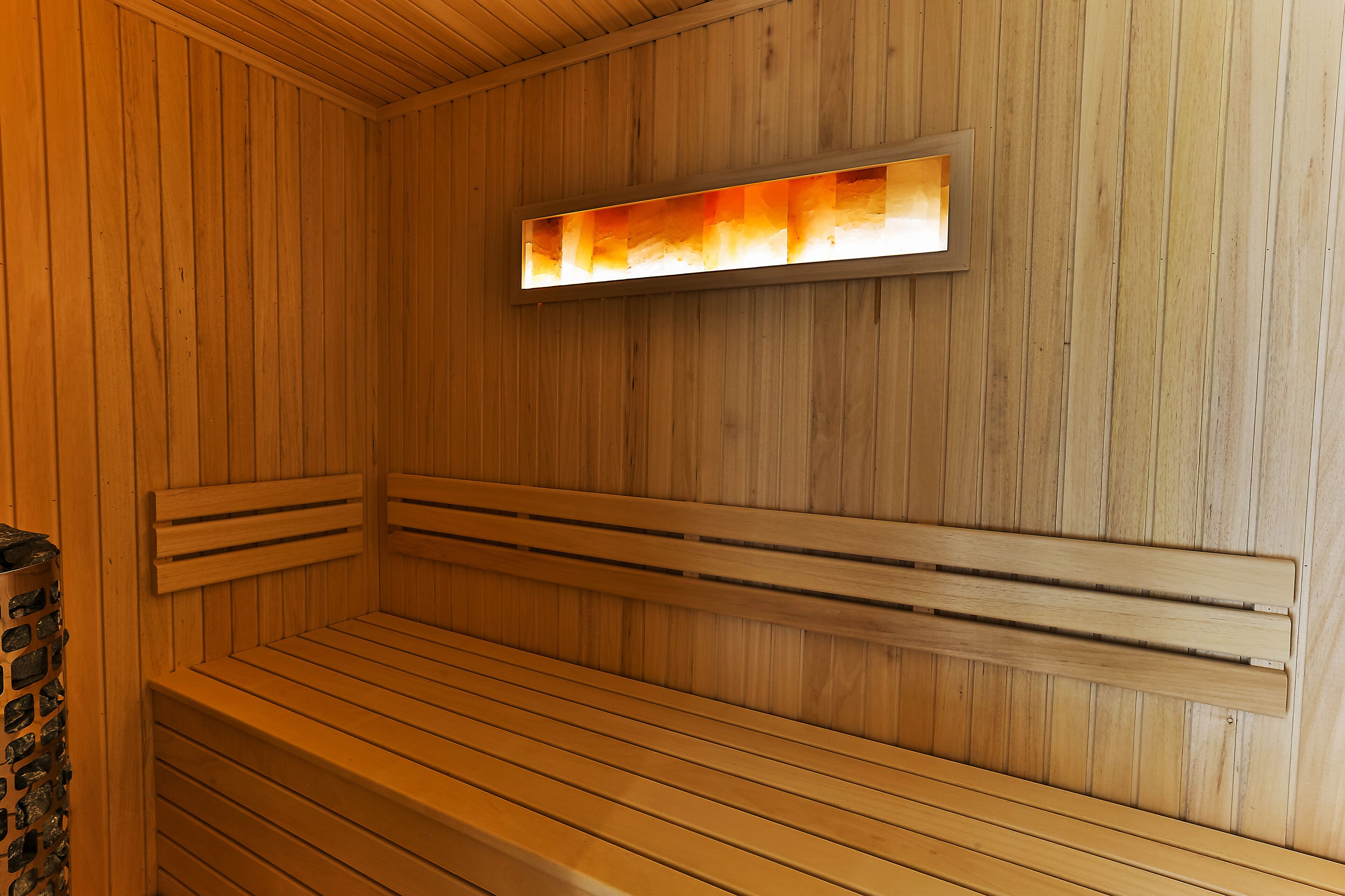 A sauna with wooden benches and a wall-mounted light fixture.