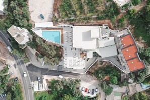 An aerial view of a modern hotel with a swimming pool, multiple outdoor seating areas, and a parking lot. - Hotel kingStone Budva (Przno)