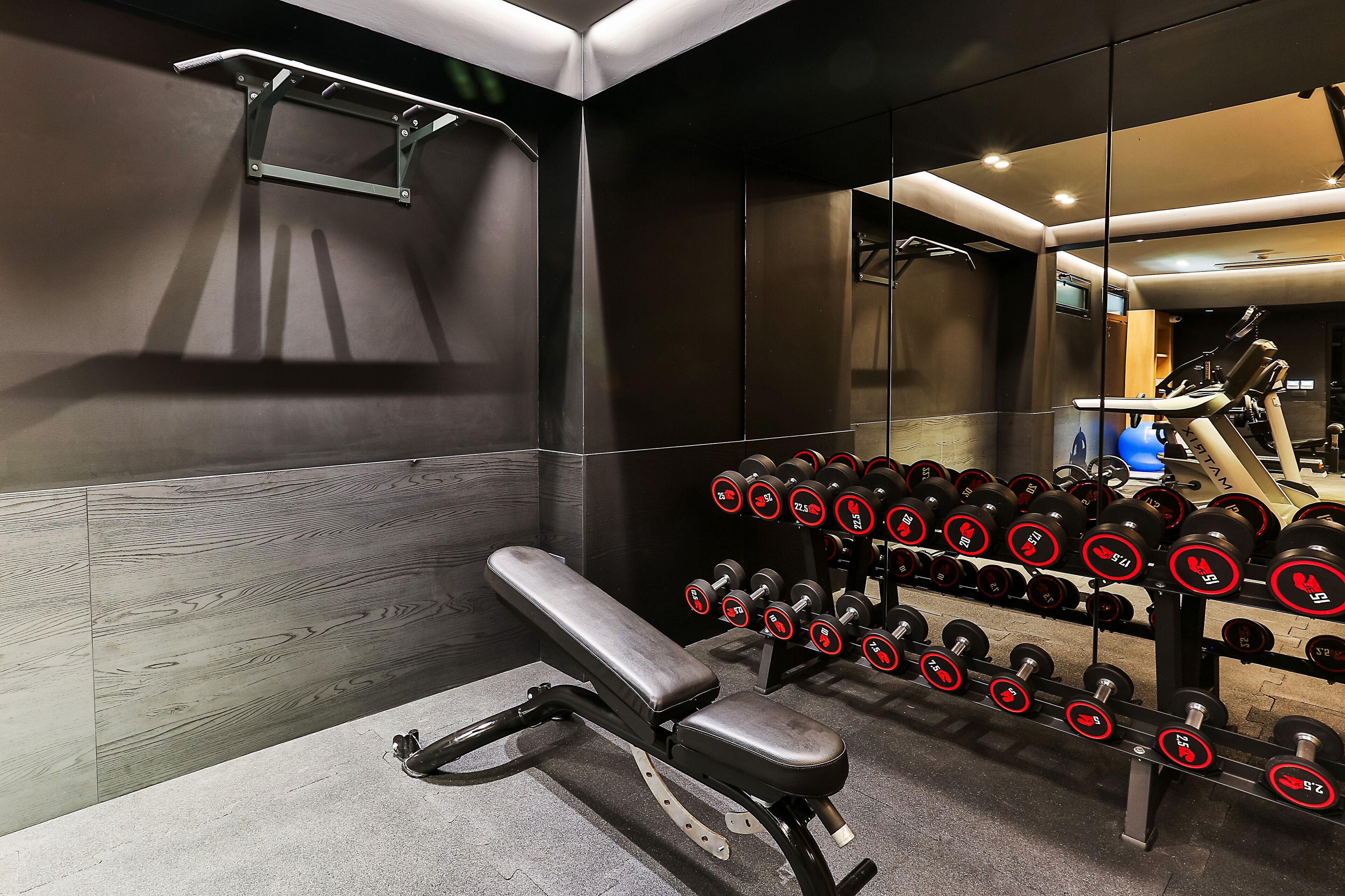 Una palestra con panche, manubri e un tapis roulant.