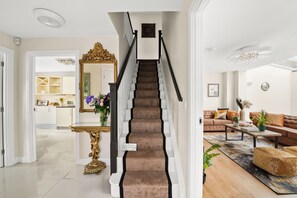 Staircase leads to an upper level, adjacent to a cozy living area with a leather sofa and decorative accents.