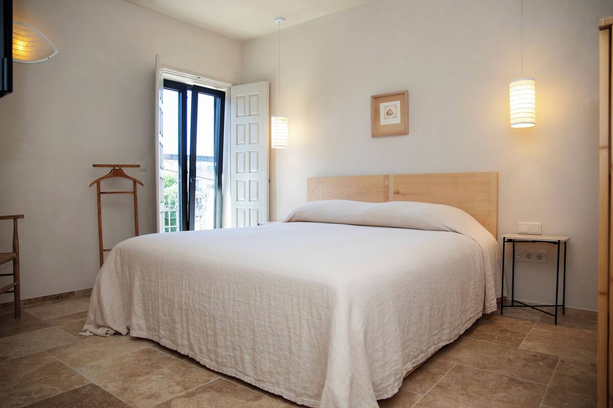 Ein Schlafzimmer mit einem großen Bett, einem hölzernen Kopfteil, einem Nachttisch und einer Pendelleuchte.