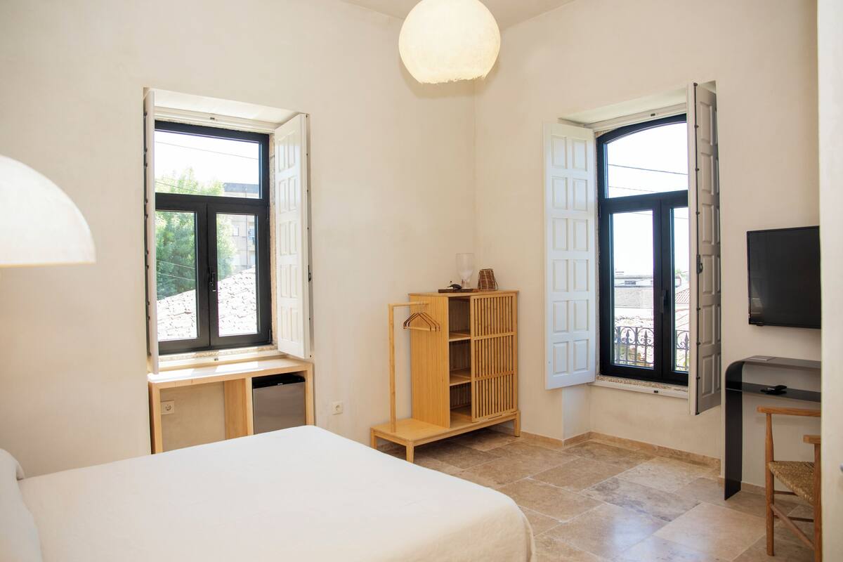 Ein Schlafzimmer mit einem Bett, einem Holzschrank, einem Schreibtisch und einem Fernseher.