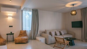 En moderne stue med sofa, lænestol, sofabord og et TV ophængt på væggen.