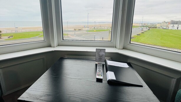 A room with a large window overlooking a beach and a road. - The Norton (Hartlepool)