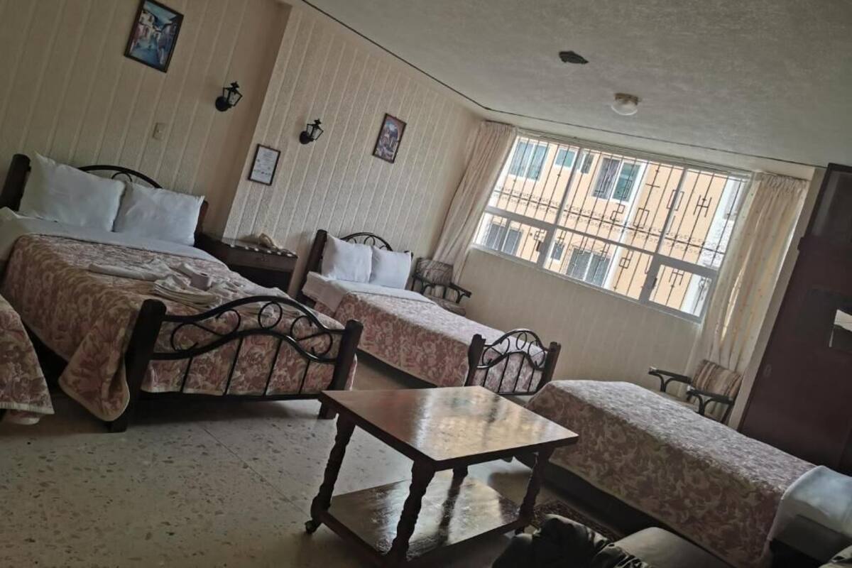 A room with two beds, a table, and a window with a view of buildings.