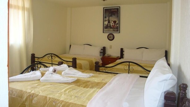 A hotel room with two beds, a poster of the Eiffel Tower, and a bedside table with a lamp. - Hotel Los Angeles  (Tulancingo)