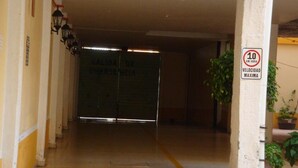 A hallway with a glass door labeled "SALIDA DE EMERGENCIA" and a speed limit sign of "10 KM/HORA". - Hotel Los Angeles  (Tulancingo)