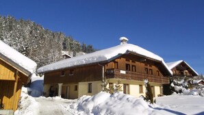 A wooden chalet with a balcony, surrounded by snow-covered trees and a clear blue sky. - Wifi, Ground floor, terrace, tv, 32m², Les Gets (Les Gets)