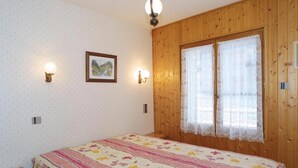 A bedroom with a bed, wooden walls, a window with lace curtains, and wall-mounted lights. - Wifi, Ground floor, terrace, tv, 32m², Les Gets (Les Gets)